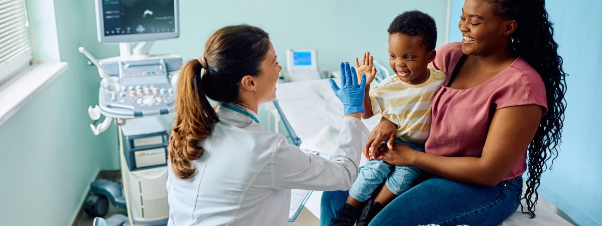 A doctor gives their child patient a high five in a clinic setting