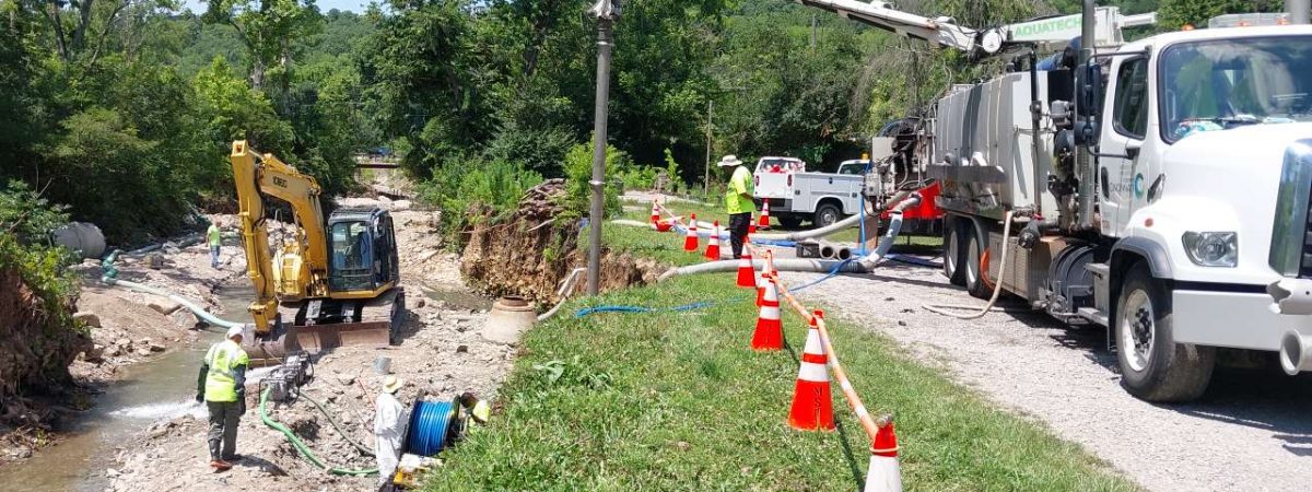 sewer district crews and equipment at creek bank