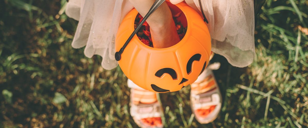 Child reaching into Halloween candy bucket